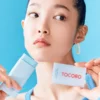 Modelo aplicando el Tocobo Cotton Soft Sun Stick en el rostro.