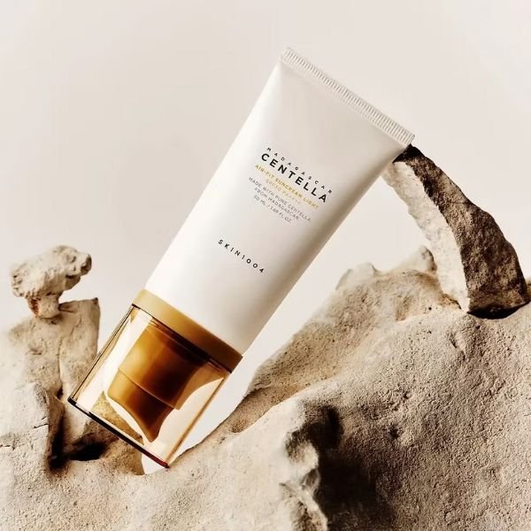 Madagascar Centella Air-Fit Suncream Light – Fotografía artística Protector solar Madagascar Centella Air-Fit Suncream Light de SKIN1004 colocado sobre rocas en una composición artística